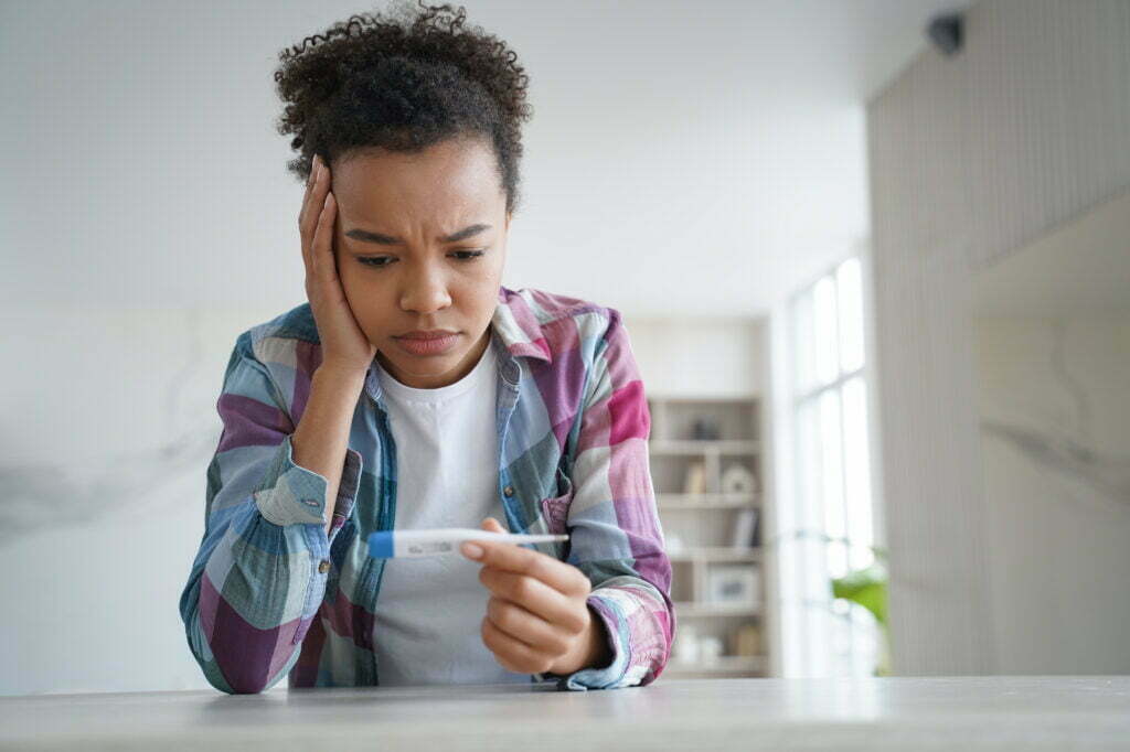 How Do I Prove Credibility of My Symptoms? Sad African American Girl Looks At Thermometer Ha 2022 08 02 00 50 04 Utc 1024x682