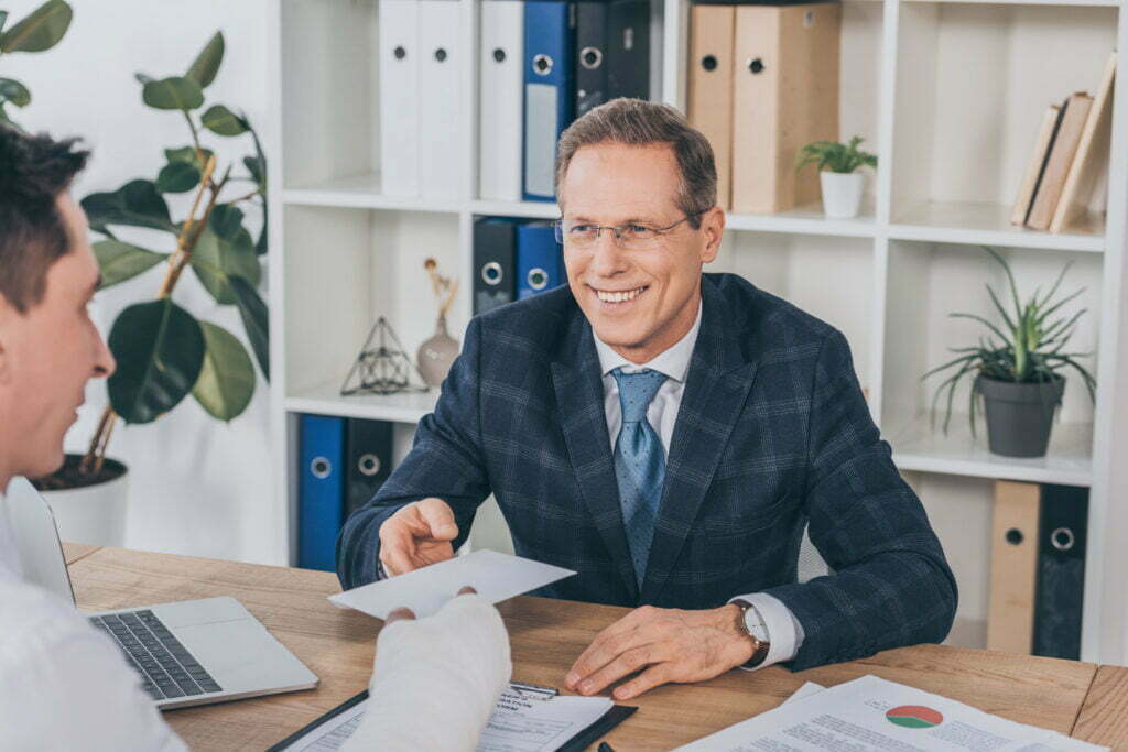 Is My Employer Required to Carry Workers Comp Insurance? Worker With Broken Arm Giving Paper To Businessman 2022 12 08 03 54 19 Utc 1024x683
