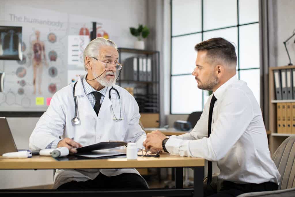 Company Doctor Visit Implies an Accepted Claim, Right? Businessman And Aged Doctor Talking At Medical Off 2021 10 07 05 11 55 Utc 1024x683